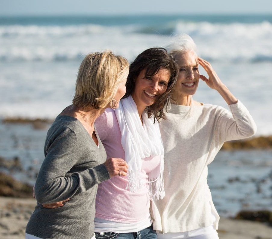 Tres mujeres de distintas edades caminando juntas por la playa