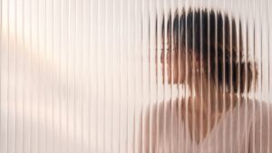 Mujer vista a través de un vidrio texturizado que difumina su rostro — la niebla mental en la menopausia