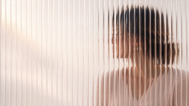 Mujer vista a través de un vidrio texturizado que difumina su rostro — la niebla mental en la menopausia